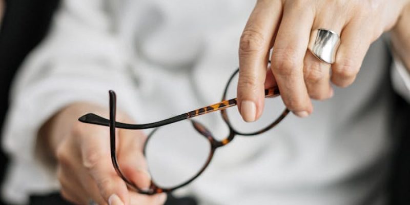Close-up of a woman holding glasses, symbolizing thought and professionalism.